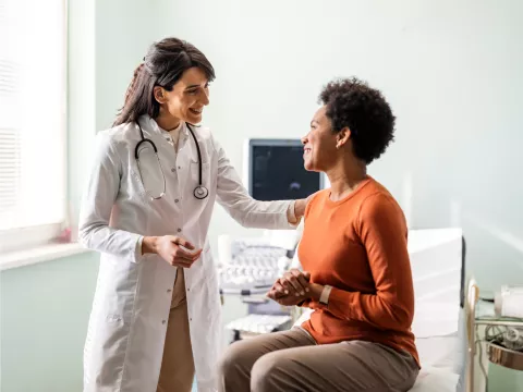 A woman talking with her doctor in an exam in room.