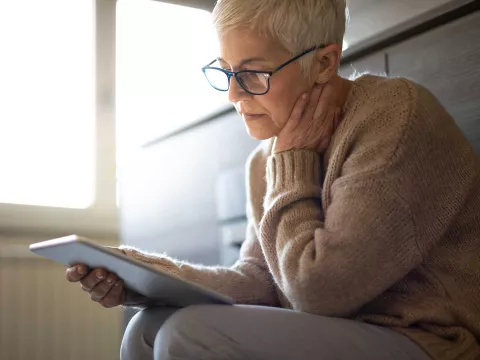 A senior seriously reading while on her tablet.